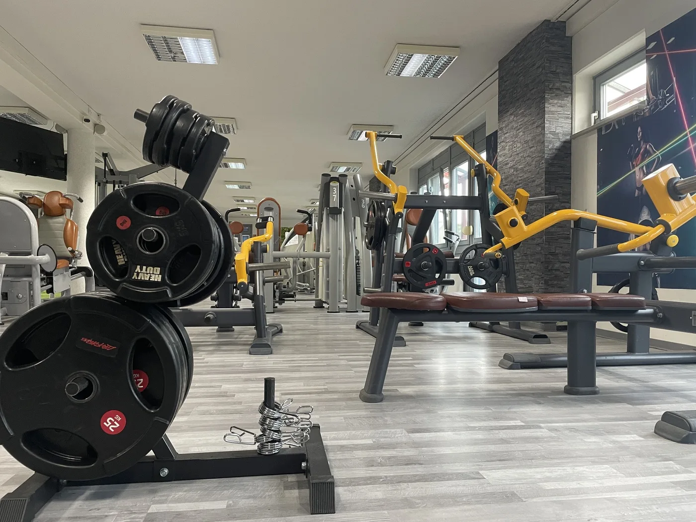 Blick durch die Trainingshalle mit Hantelscheiben und Bänken